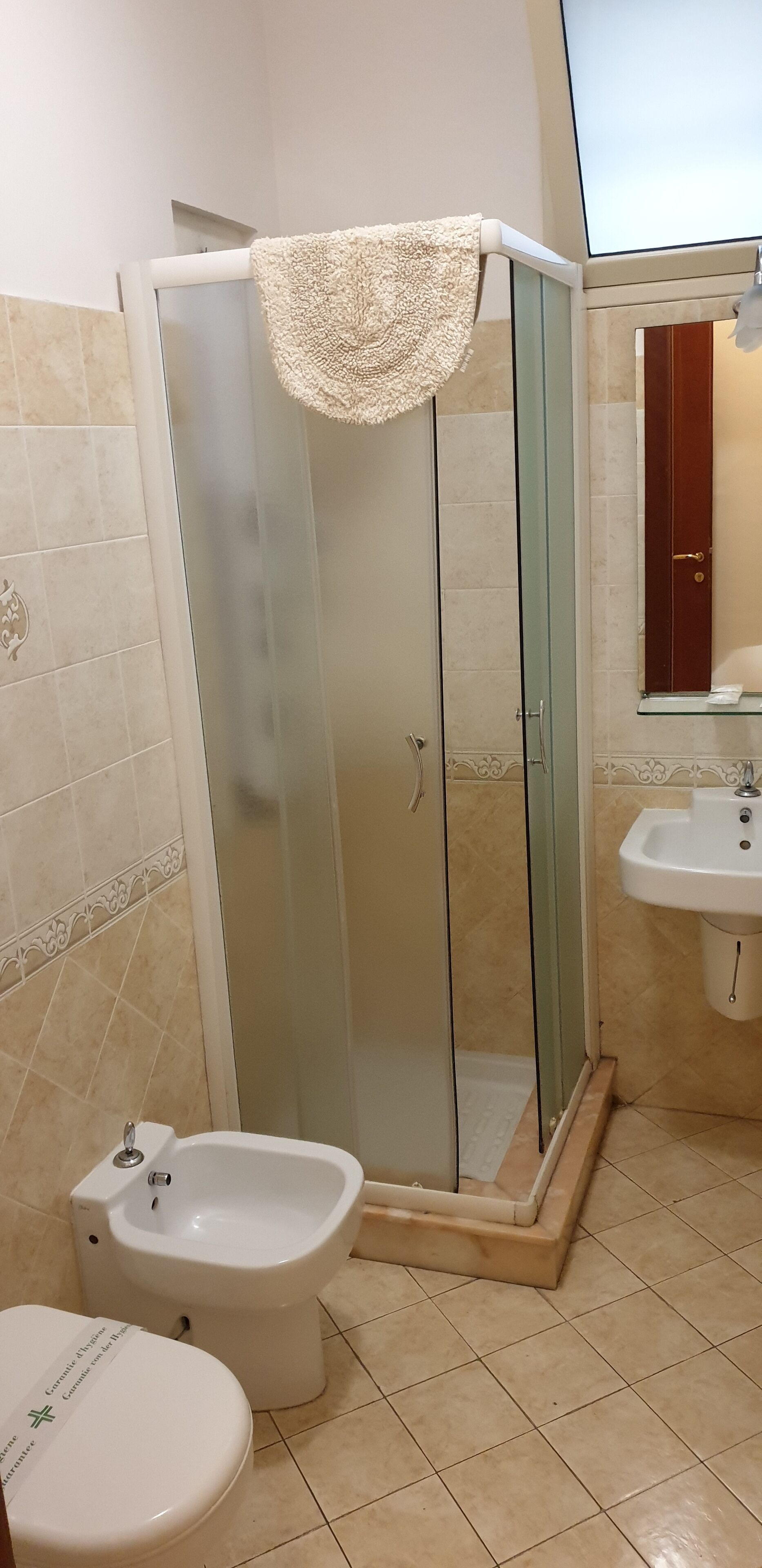 A bathroom with a glass-enclosed shower, a bidet, a sink, and a toilet.