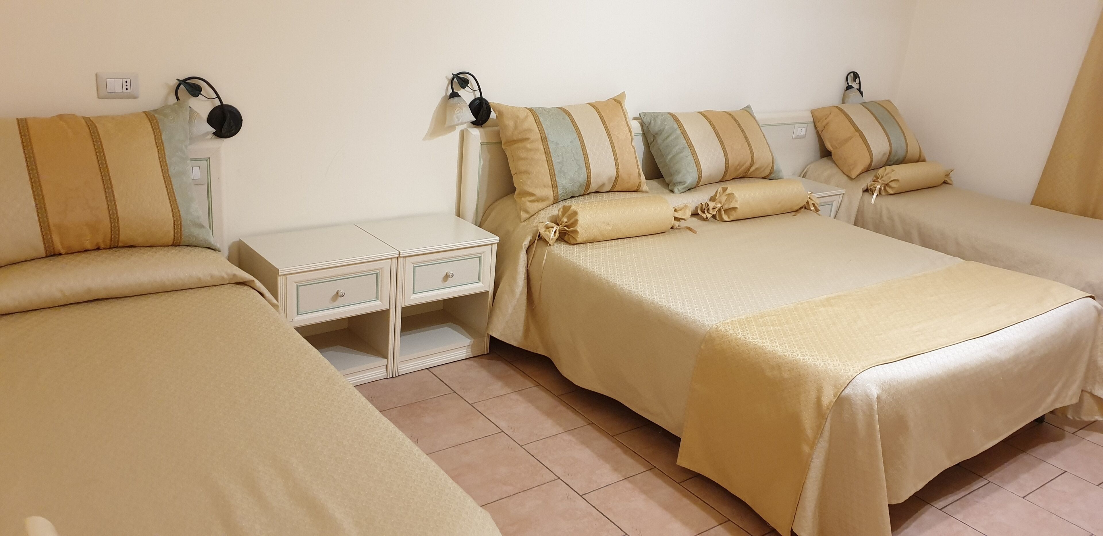 Een hotelkamer met twee eenpersoonsbedden, elk met hoofdeinde en kussens, een nachtkastje met een lamp en een klein dressoir.