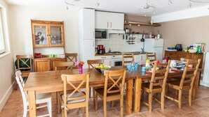 A kitchen with a wooden table and chairs, white cabinets, a microwave, and various kitchen items.