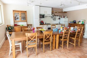 Una cocina con mesa y sillas de madera, armarios blancos, un microondas y varios utensilios de cocina.