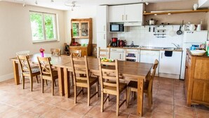 A kitchen with wooden cabinets, a dining table with chairs, and a window with greenery outside.
