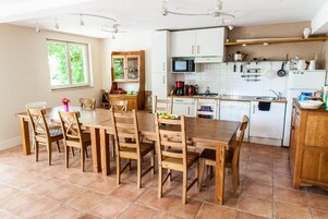 Una cocina con armarios de madera, una mesa de comedor con sillas y un ventanal con follaje exterior.