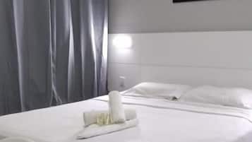 Quarto de hotel com cama, secretária e cadeira.
