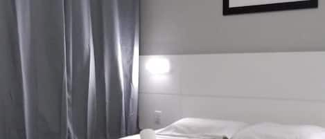 A hotel room with a bed, a desk, and a chair.