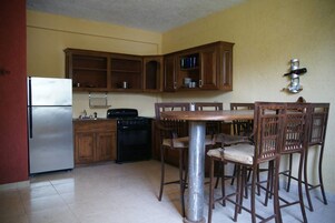 Una cocina con armarios de madera, un refrigerador de acero inoxidable, una estufa y una mesa de comedor con sillas.