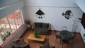 A sunlit patio with a sofa, chairs, a coffee table, and a dining table. - Corail Suites (Petionville)