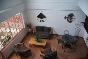 Un patio iluminado por el sol con un sofá, sillas, una mesa de centro y una mesa de comedor.