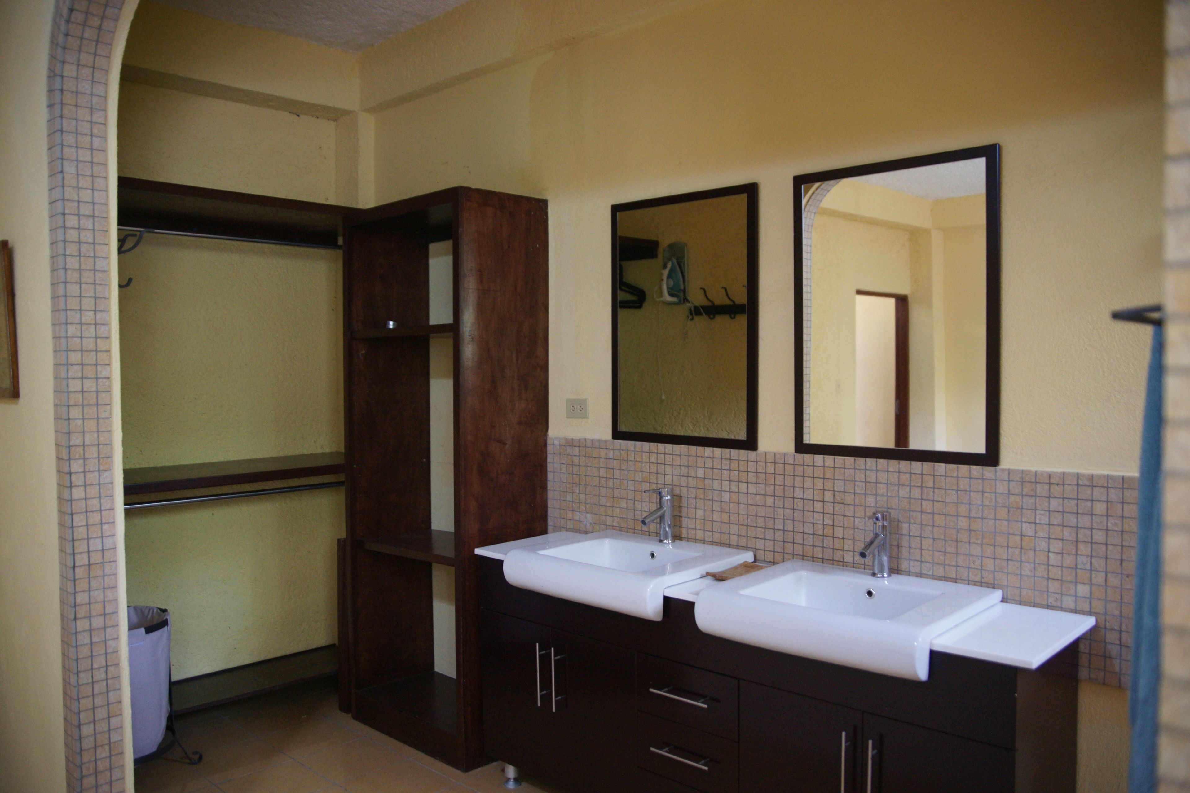 Un baño con dos lavamanos, un espejo y un mueble de madera.