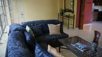 A living room with a sofa, a coffee table, and a dining area with a table and chairs.
