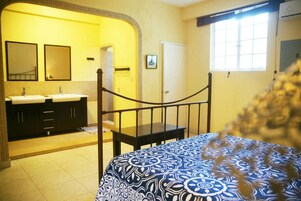 Un dormitorio con cama, ventana y baño con dos lavamanos y espejos.