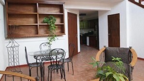A dining area with a table and chairs, a wooden shelf, and a potted plant. - Corail Suites (Petionville)