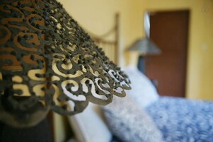 Una cama con una colcha estampada y un cabecero de metal decorativo.