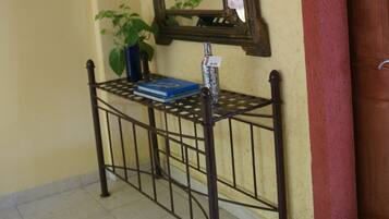 A hallway with a metal bench, a mirror, a potted plant, and a wooden door.