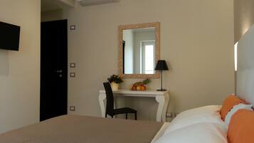A hotel room with a bed, a desk with a chair, a mirror, and a television on the wall.