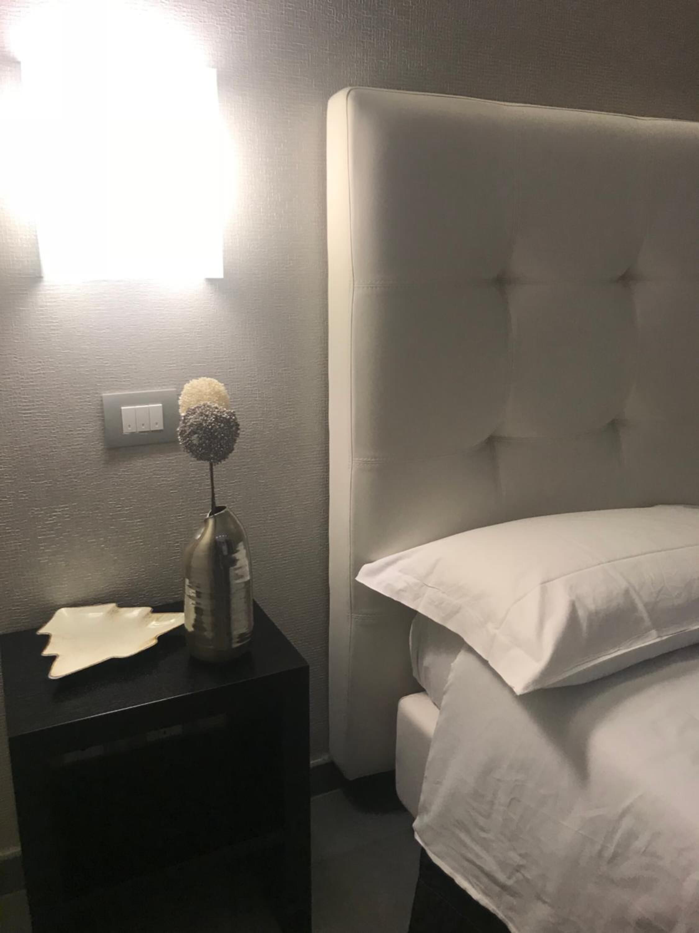 Une chambre à coucher avec un grand lit, une table de chevet avec une lampe et un luminaire fixé au mur.