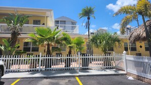 A yellow building with a white fence, palm trees, and a clear blue sky. - Silver Sands Motel (Clearwater Beach)