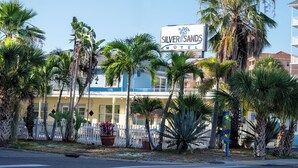 A Silver Sands Motel with a white fence, palm trees, and a clear blue sky. - Silver Sands Motel (Clearwater Beach)