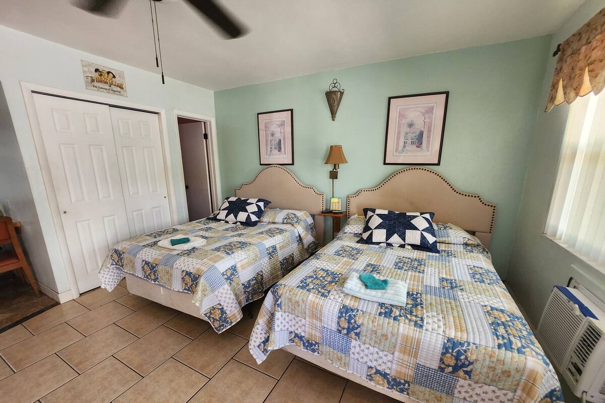 Une chambre avec deux lits, une porte, une lampe et un radiateur.