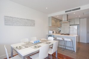 Una cocina moderna con armarios blancos, un microondas y una campana extractora de acero inoxidable.