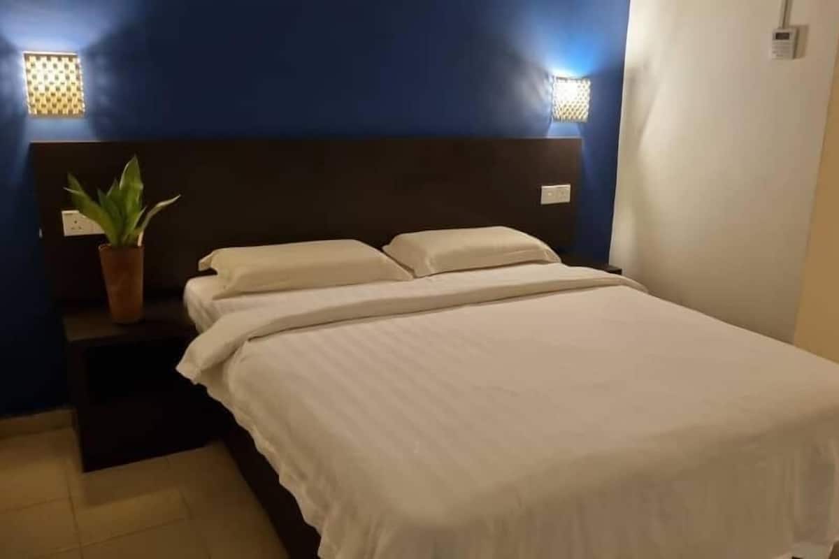 A bedroom with a bed, a nightstand, and a potted plant.