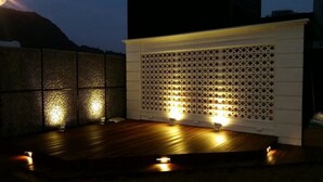 Une terrasse extérieure dotée d’un plancher en bois et d’un mur décoratif blanc orné d’un motif en treillis.