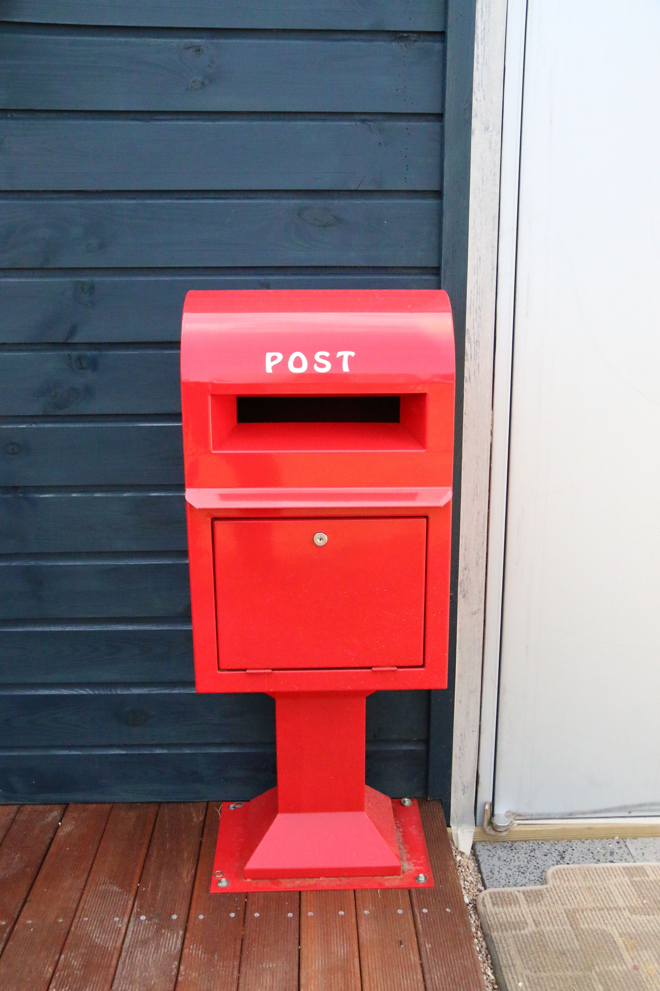A red post box against a dark wooden background.