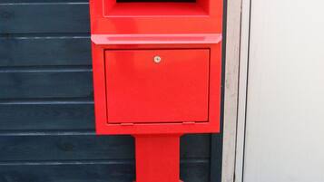 A red post box against a dark wooden background.