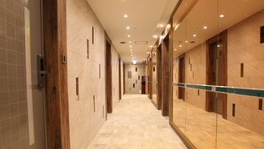 Un couloir doté d’un sol en marbre, de portes en bois et d’un mur recouvert de miroirs.
