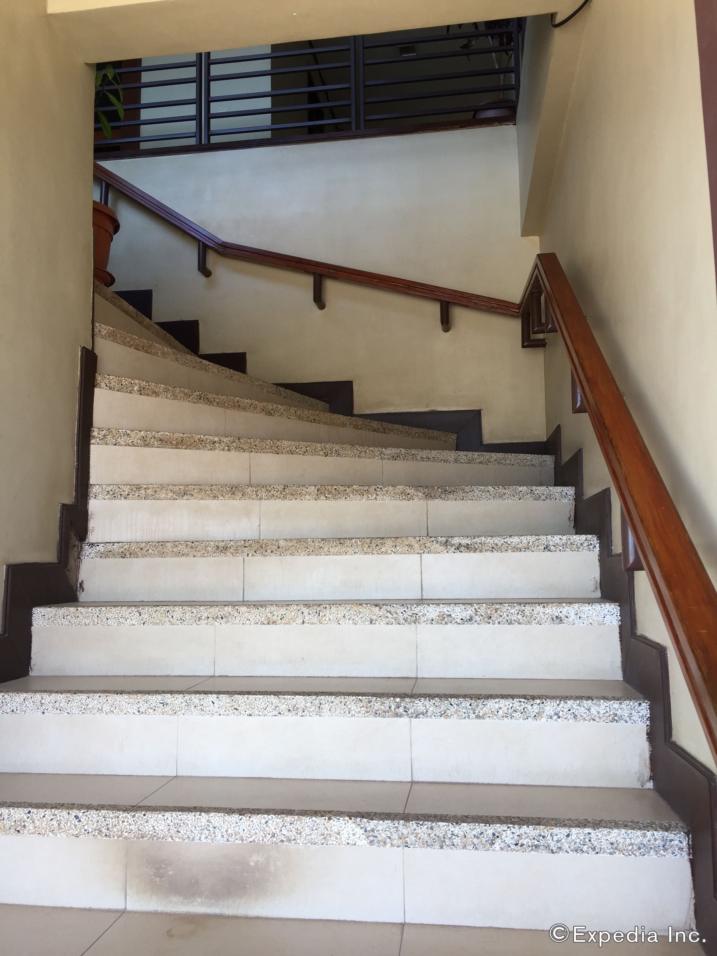 A staircase with a wooden handrail and a metal railing, leading to an upper floor.