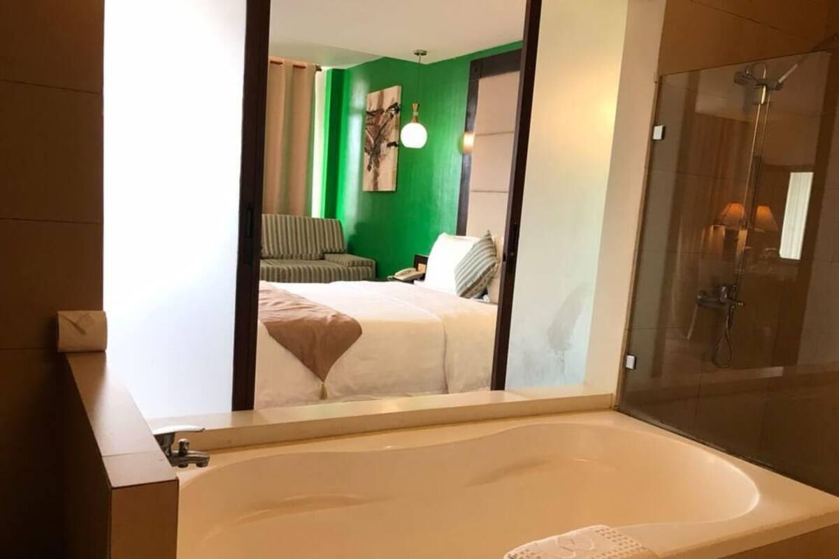 Un baño moderno con una bañera grande, ducha y pared verde.