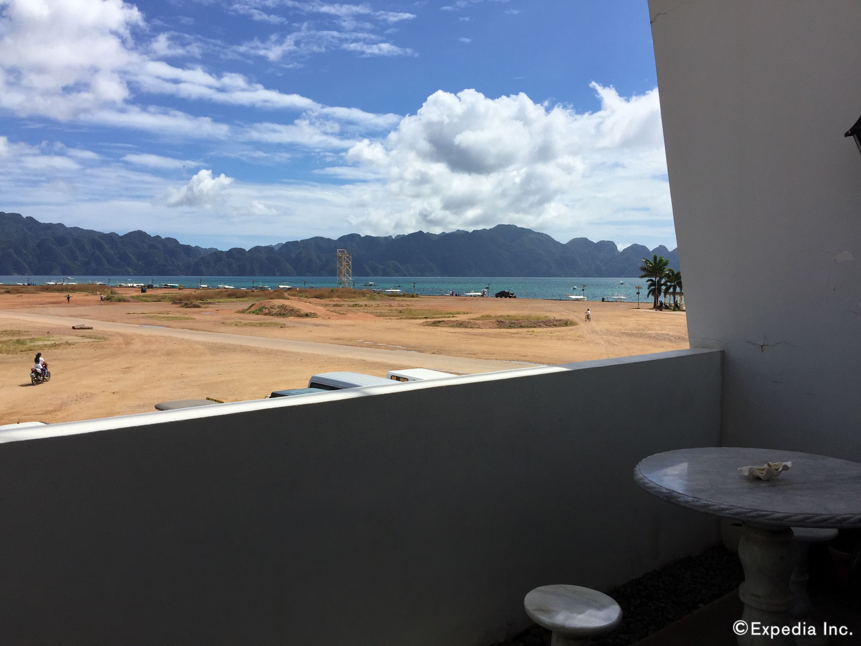 Ein Balkon mit Blick auf einen Strand, Berge und einen klaren Himmel.