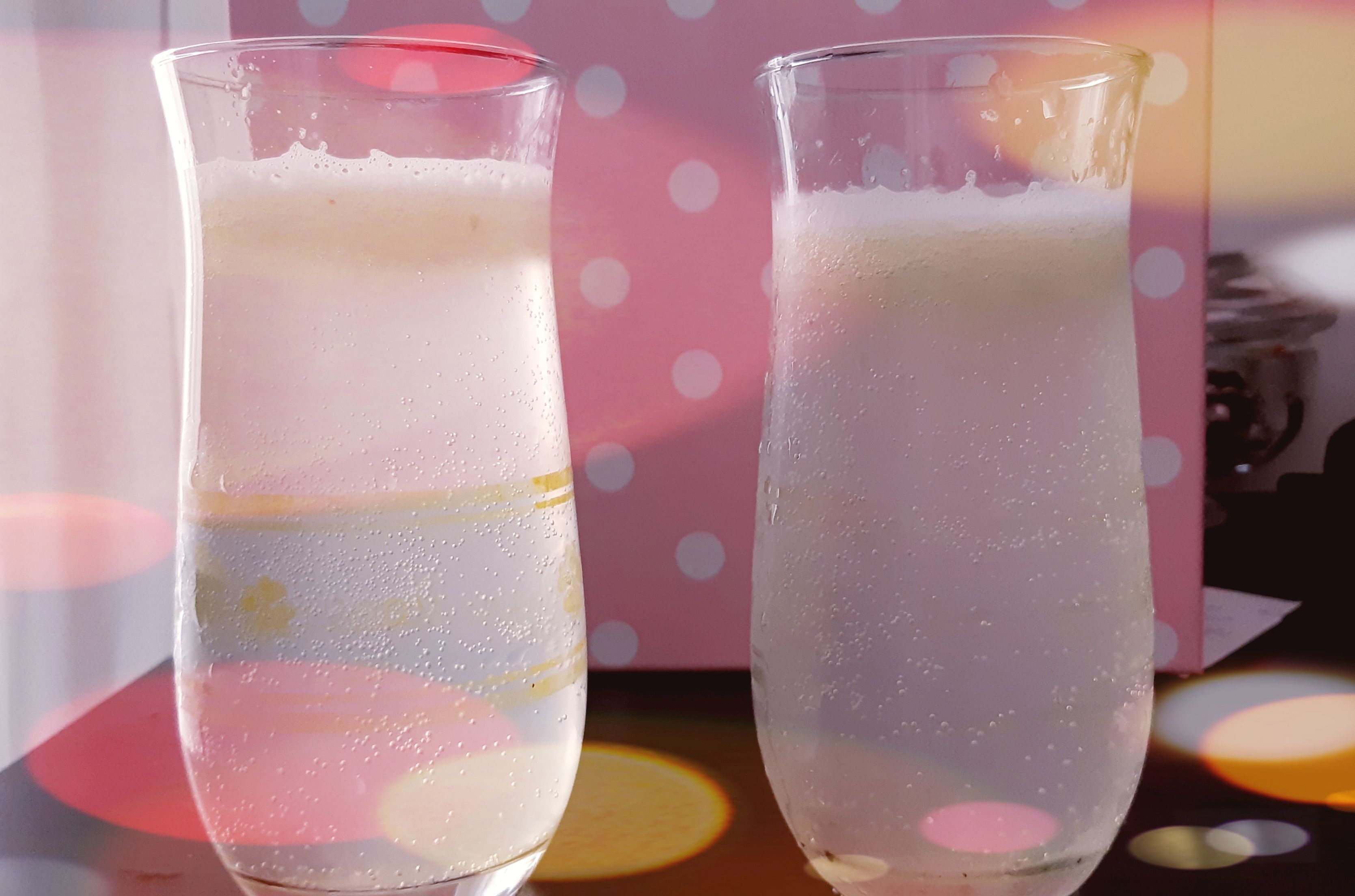 Dos vasos de una bebida clara y efervescente sobre una mesa con un fondo de lunares.