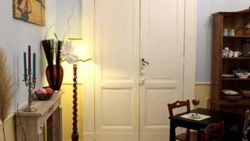 Una habitación con chimenea, una mesa de comedor con sillas, una estantería y una puerta.