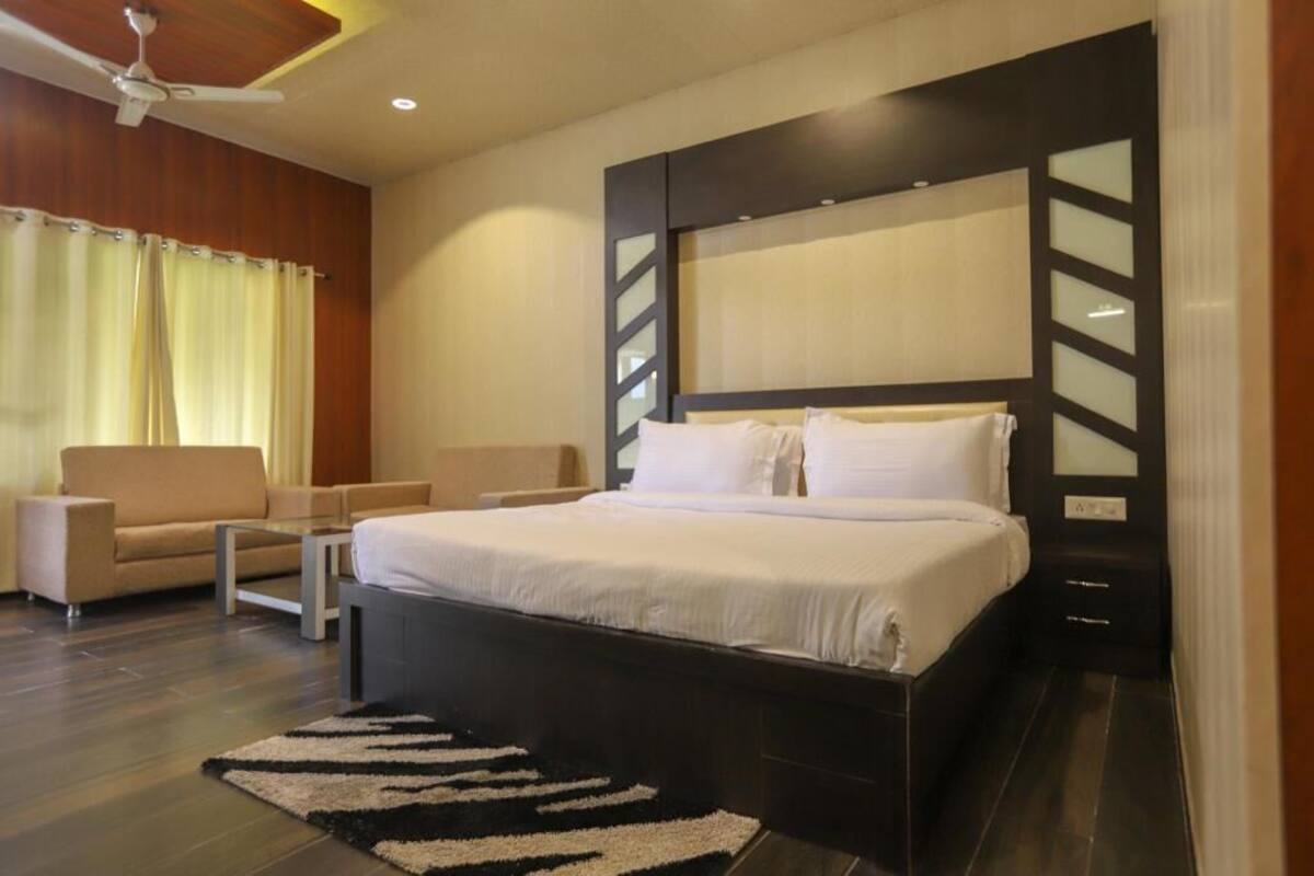 Ein modernes Hotelzimmer mit einem großen Bett, einer Couch, einem kleinen Tisch und einem Deckenventilator.