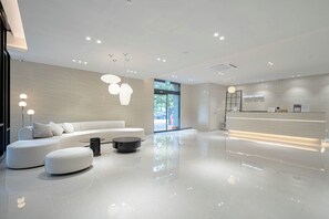 A modern hotel lobby with a reception desk, seating area, and large windows. - Airport Hotel (Busan)