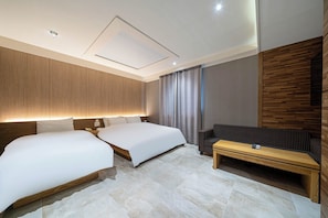 A modern hotel room with two beds, a sofa, a coffee table, and a large window with curtains. - Airport Hotel (Busan)