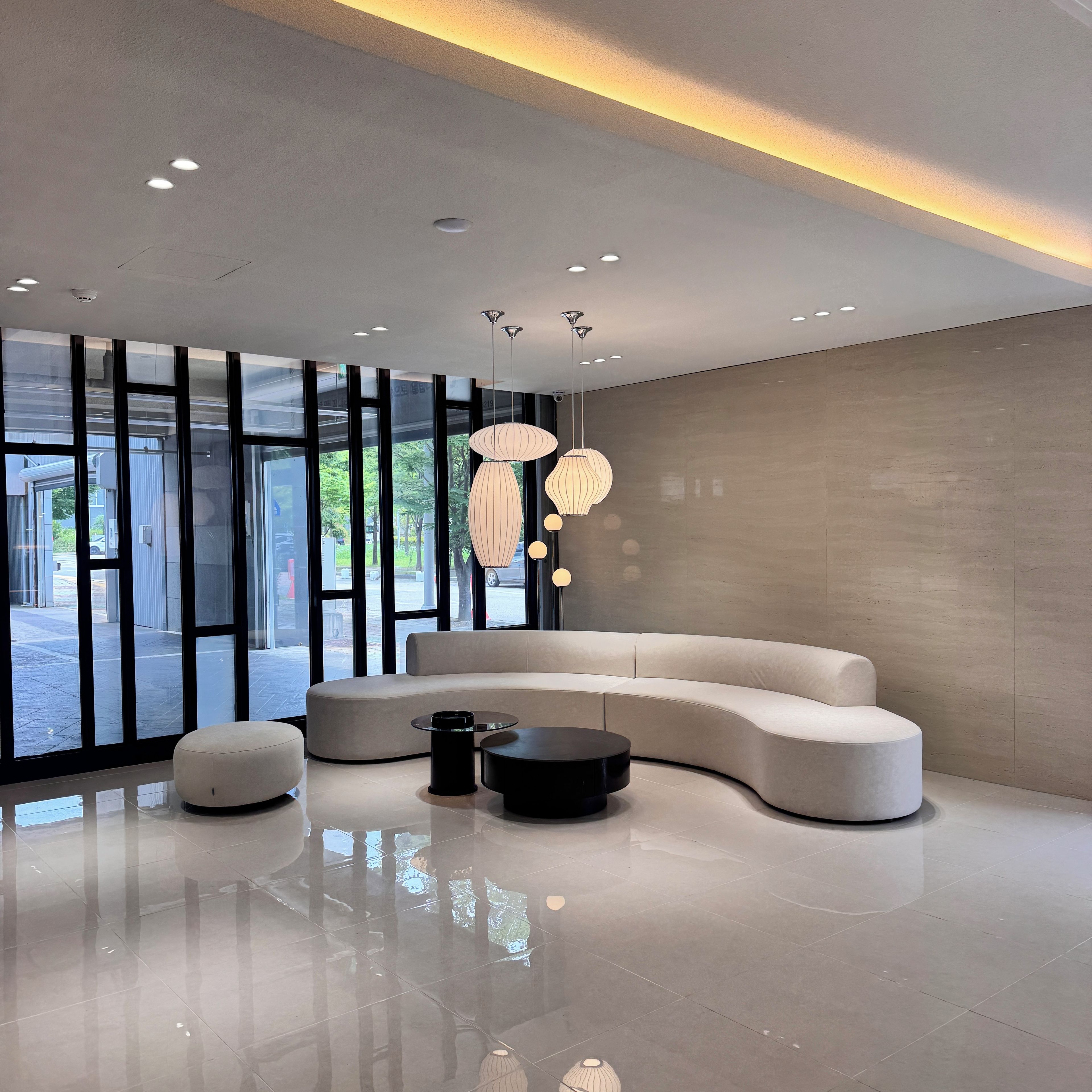 A modern interior with a curved sofa, a round coffee table, and pendant lighting.
