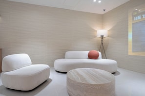 A modern, minimalist room with three white sofas and a marble coffee table. - Airport Hotel (Busan)