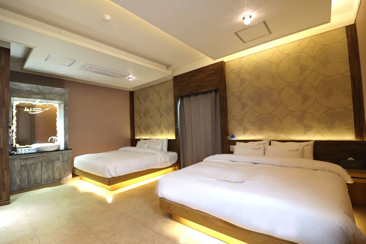 A hotel room with two beds, a large mirror, a vanity with a sink, and a patterned wall.