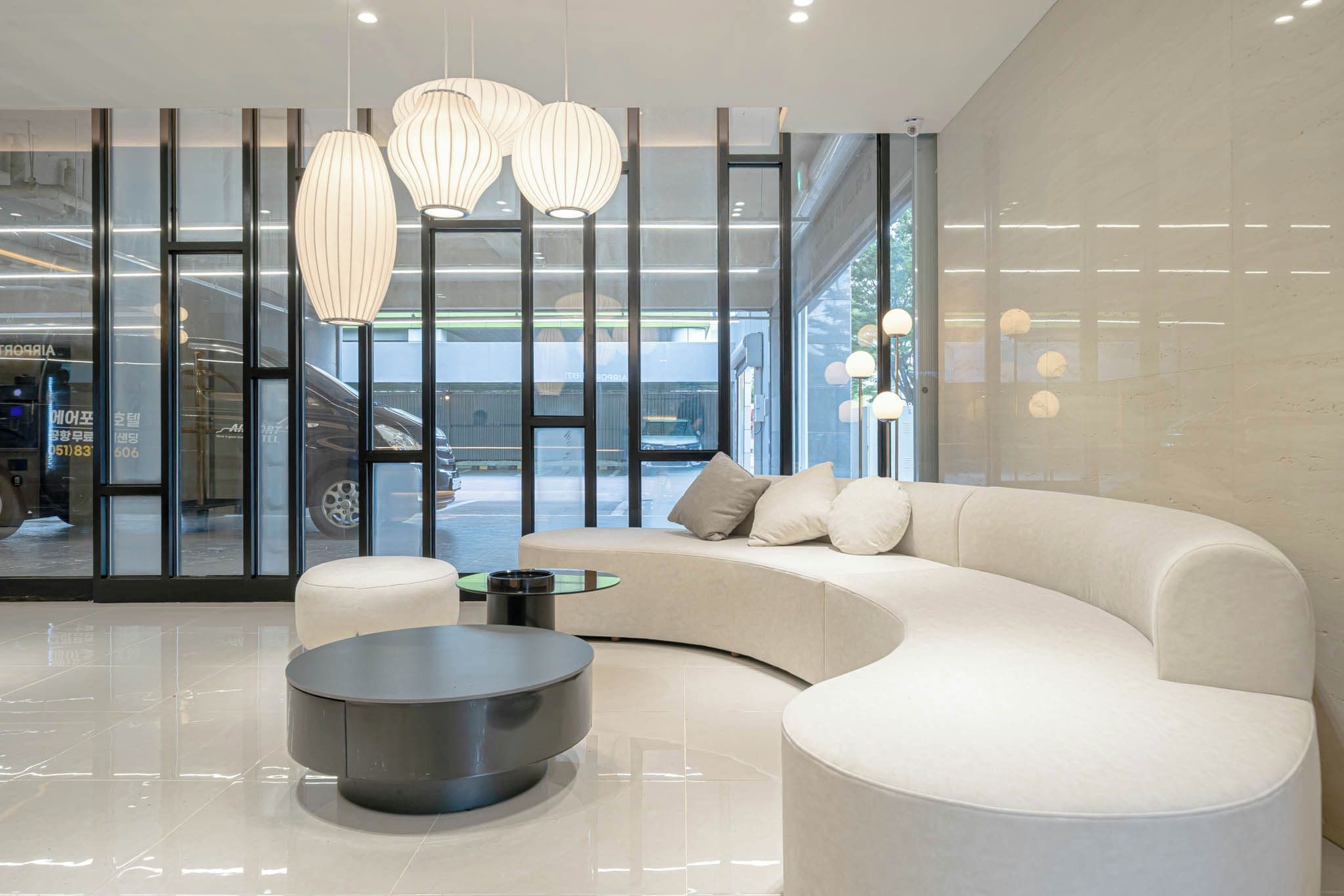 A modern interior with a curved sofa, round coffee table, and pendant lighting.