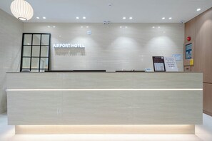 Una reception con un cartello che riporta 'AIRPORT HOTEL' e un design moderno con illuminazione a incasso.