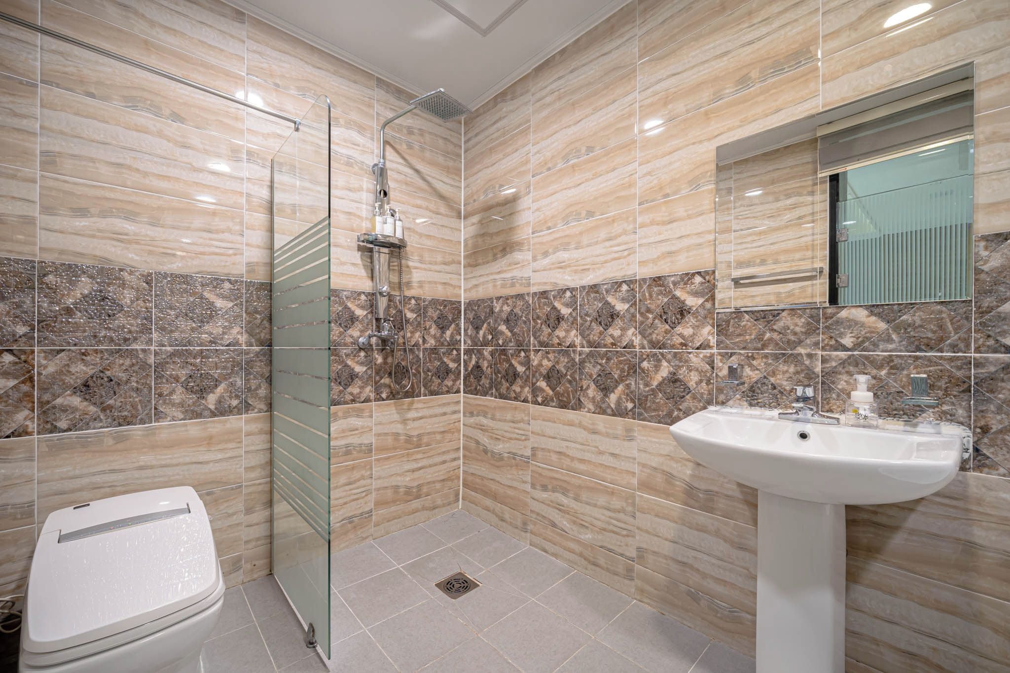 Un baño moderno con cabina de ducha de vidrio, un lavamanos blanco y un inodoro.