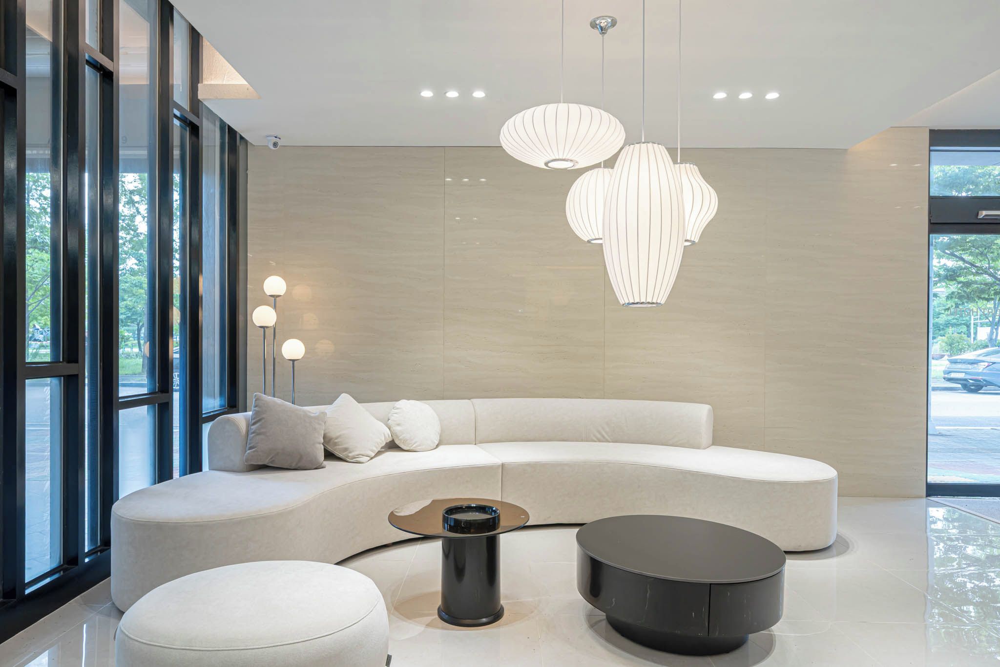 Una sala de estar moderna con un sofá curvo, una mesa de centro redonda e iluminación colgante.
