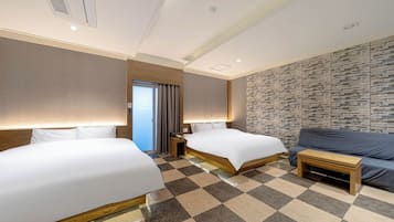 Habitación de hotel con dos camas, un sofá, piso a cuadros y una pared con textura.