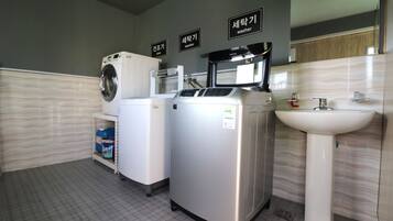 A modern bathroom with a washing machine, dryer, and sink.
