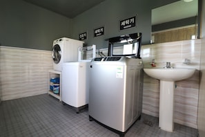 A modern bathroom with a washing machine, dryer, and sink. - Airport Hotel (Busan)