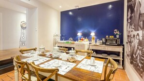 A dining area with a wooden table set for four, a microwave, and a refrigerator. - Vacanze Romane Rooms (Rome)
