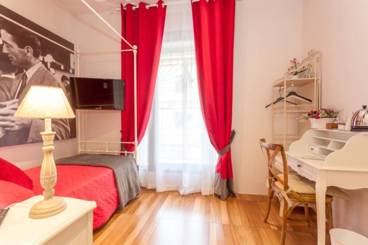 A bedroom with a bed, a desk, a chair, a TV, and a wardrobe.