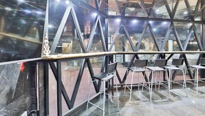 A modern interior with a geometric glass and metal design, featuring a central table with chairs and a visible brick wall in the background. - 2 Heaven Hotel (Busan)