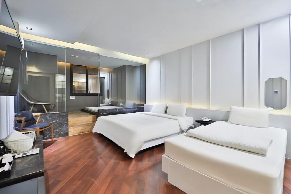 A modern hotel room with a large bed, a desk, and a seating area.